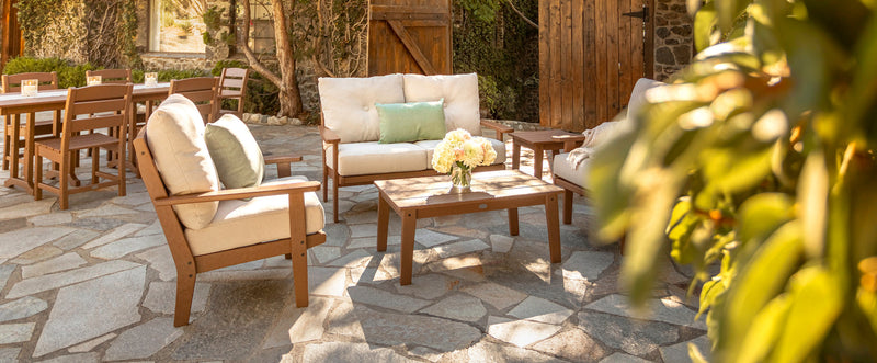 A POLYWOOD Lakeside 4 Piece Deep Seating Set in Teak with Natural Linen cushions is arranged on a stone patio.