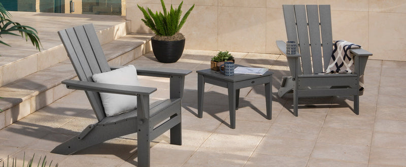 A POLYWOOD Quattro Folding Chair 3 Piece Adirondack Set in Slate Grey sits on a tile patio.