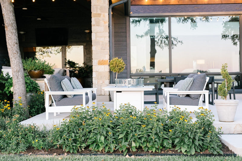 White POLYWOOD Prescott Deep Seating Chairs with grey cushions surround a white Square 42 Inch Fire Pit Table on a patio.