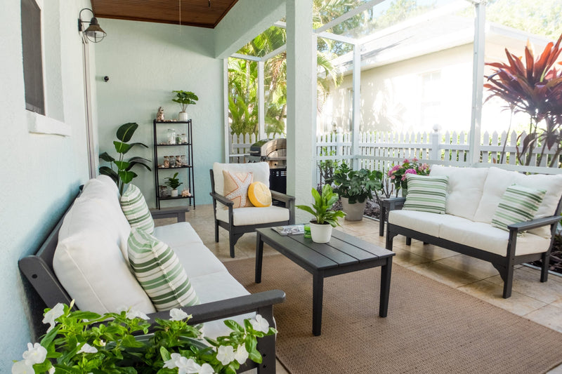 A POLYWOOD Vineyard 5 Piece Deep Seating Set in Black with Natural Linen cushions sits on a tile patio with potted plants.