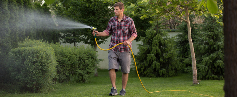 A man waters grass with a garden hose.