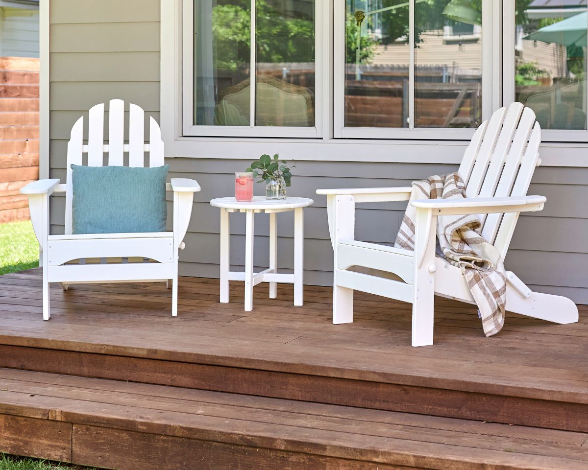 A clean white POLYWOOD Classic Folding Adirondack Set sits on a covered porch,