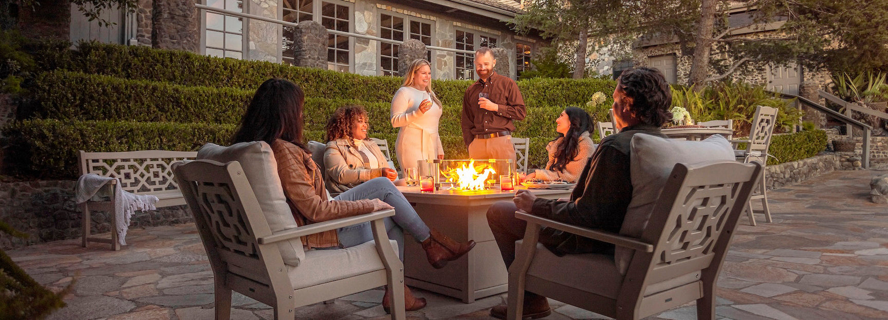 People gather around a Martha Stewart by POLYWOOD Chinoiserie 5 Piece Deep Seating Set with Fire Pit Table.