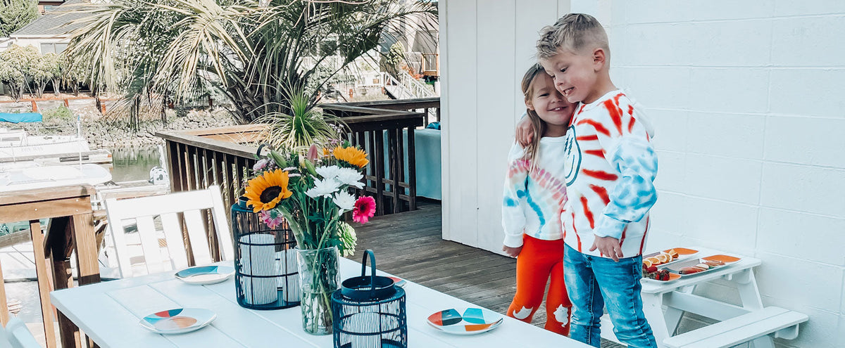 A boy and a girl stand next to a POLYWOOD Vineyard 6 Piece Rustic Farmhouse Side Chair Dining Set with Bench in White.