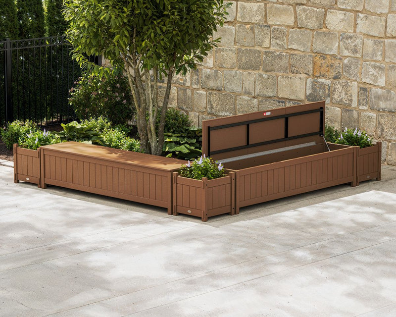 A brown POLYWOOD 72-Inch Vineyard L-Shaped Planter Storage Bench Corner Set sits on a concrete patio by a stone wall and landscaping.