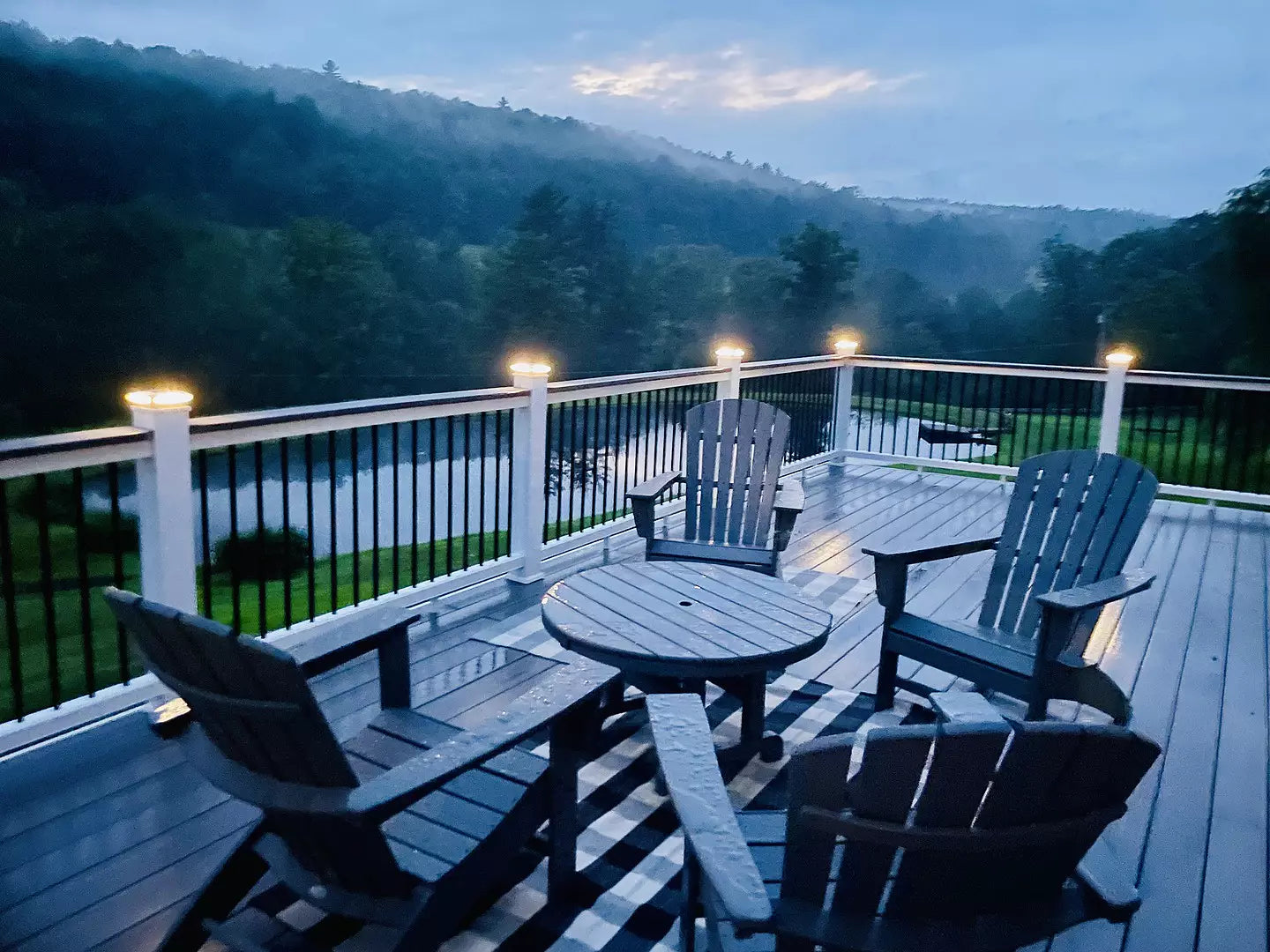 POLYWOOD South Beach Adirondack chairs and a Round 37 Inch Conversation Table in Black sit on a balcony with mountain views.
