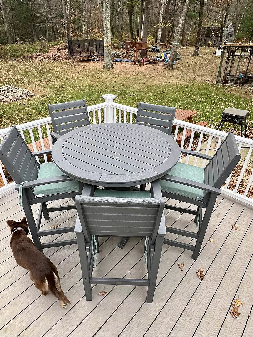 POLYWOOD dining furniture in Slate Grey with seat cushions in Glacier Spa sits on a balcony overlooking a lawn and trees.