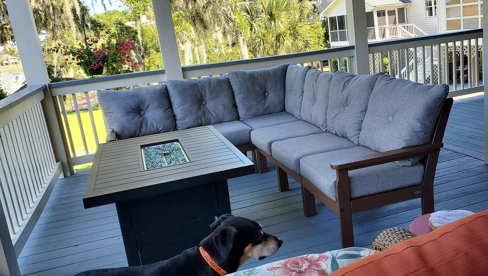 A POLYWOOD Vineyard 6 Piece Sectional in Mahogany and Sky Blue sits on a covered balcony overlooking palm trees.
