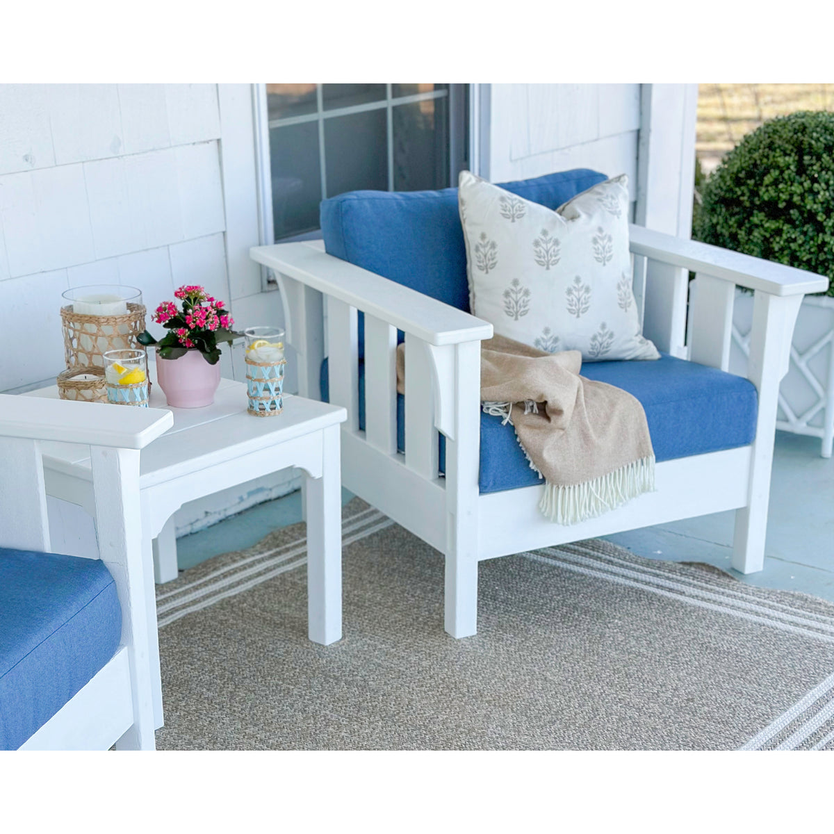 two white chairs with blue cushions and side table
