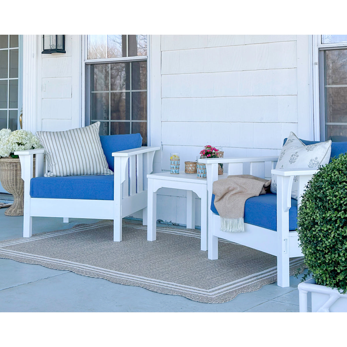 two white outdoor chairs with blue cushions and table